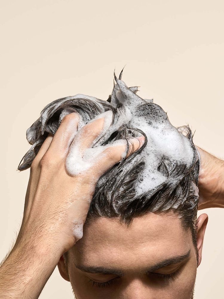 Homme appliquant un soin capillaire DermaOXY à domicile